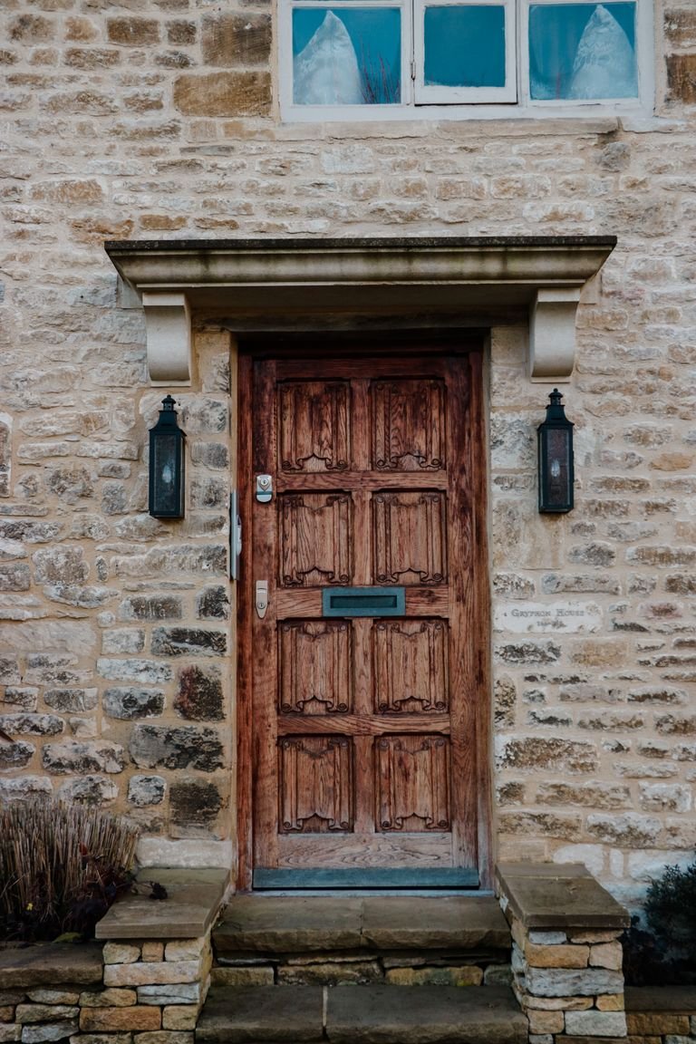 Porte d'entrée en bois sculpté dans un mur en pierre